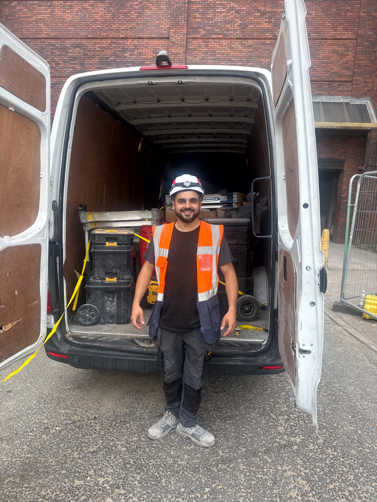 White van with open rear doors, worker in safety vest, stacked toolboxes inside — job TE-149MD082026
